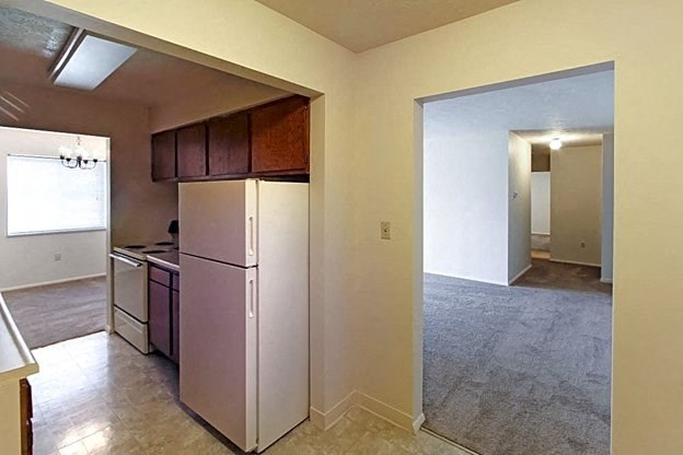 a kitchen with a white refrigerator freezer next to a stove top oven