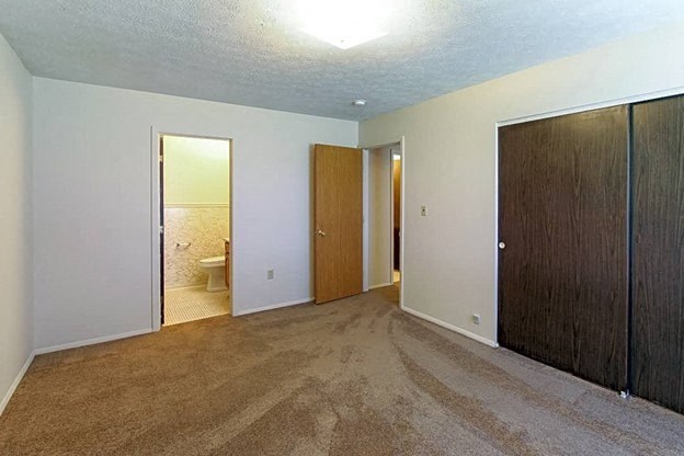 an empty room with a bathroom in the background