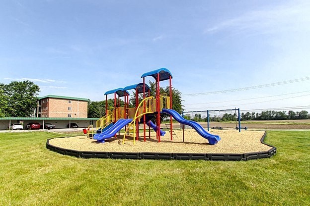 a playground with three slides in a grassy area