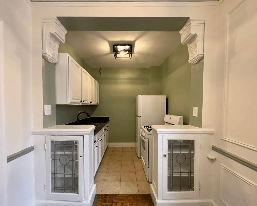 a kitchen with white cabinets and green walls