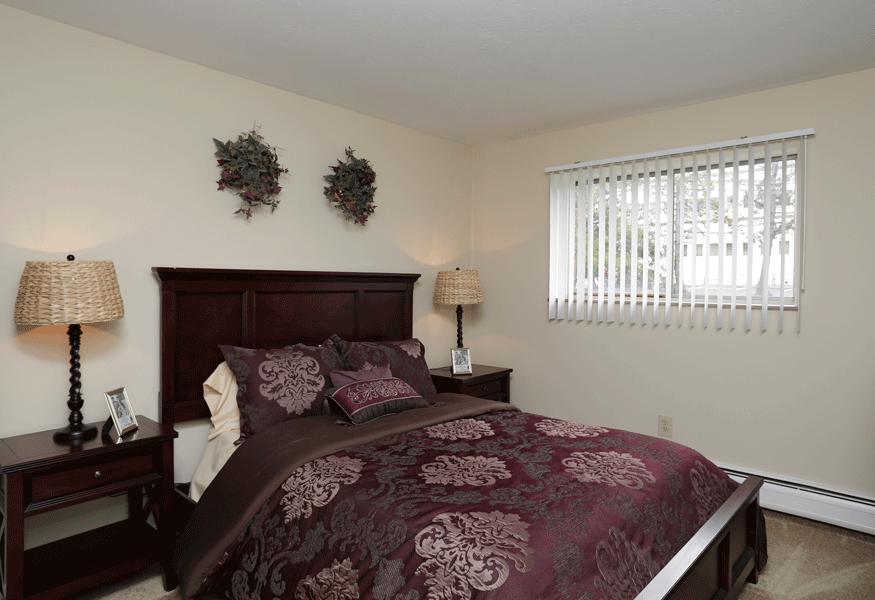 a bedroom with a bed and two lamps and a window
