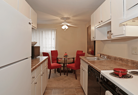 a kitchen and dining room with white appliances and a table with red chairs