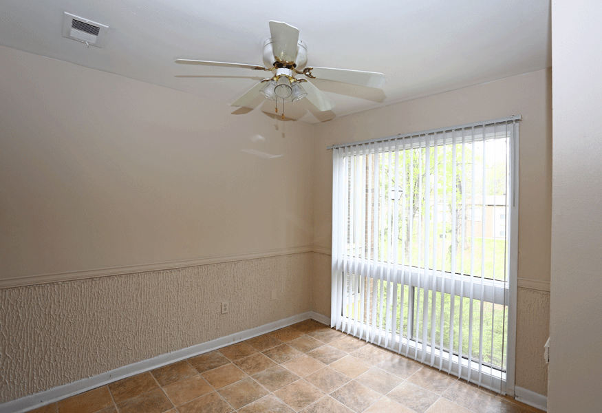 Dining room with white celling fan,  picture window with blinds, and brown tile floors.