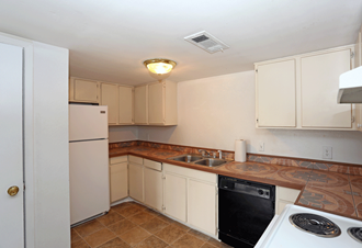 Kitchen with white cabinets, a white fridge, black dishwasher, and brown tile flooring.