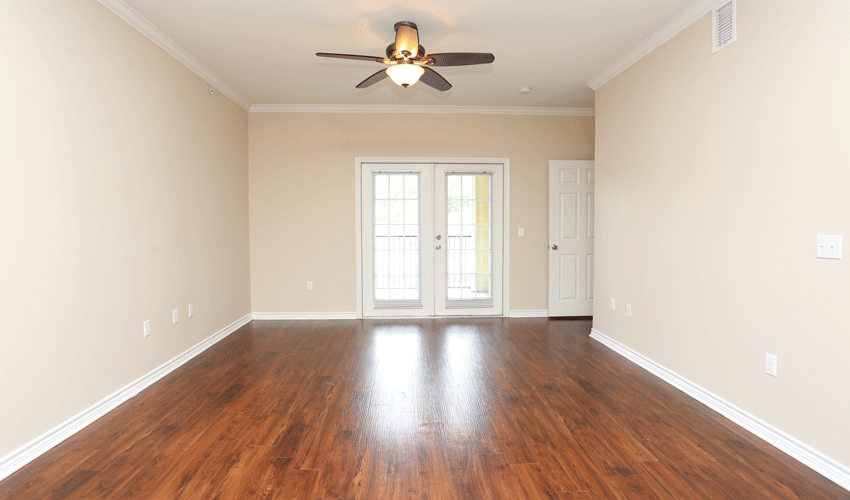 an empty living room with wooden floors and a ceiling fan