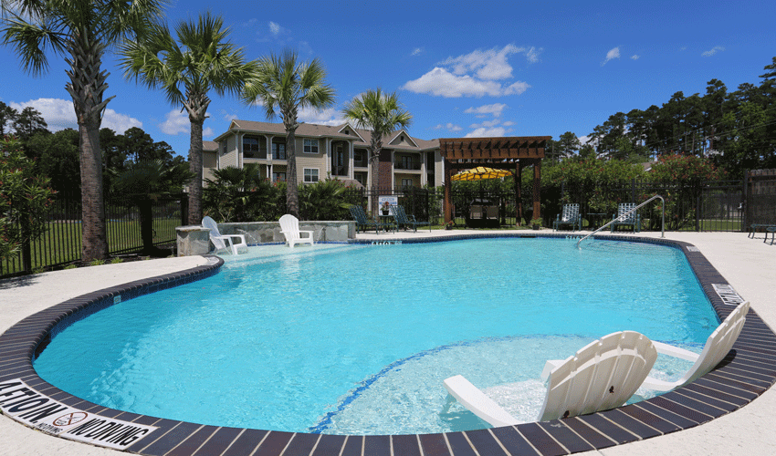 a large swimming pool with chairs and a house in the background