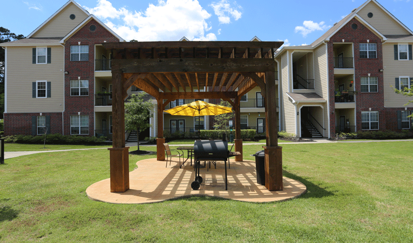 a patio with a table and umbrella in front of an apartment building