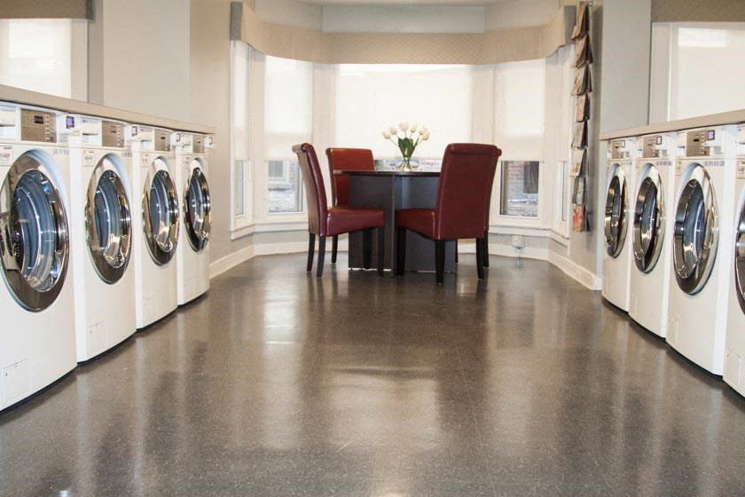 Communal laundry room with seating area and large windows.