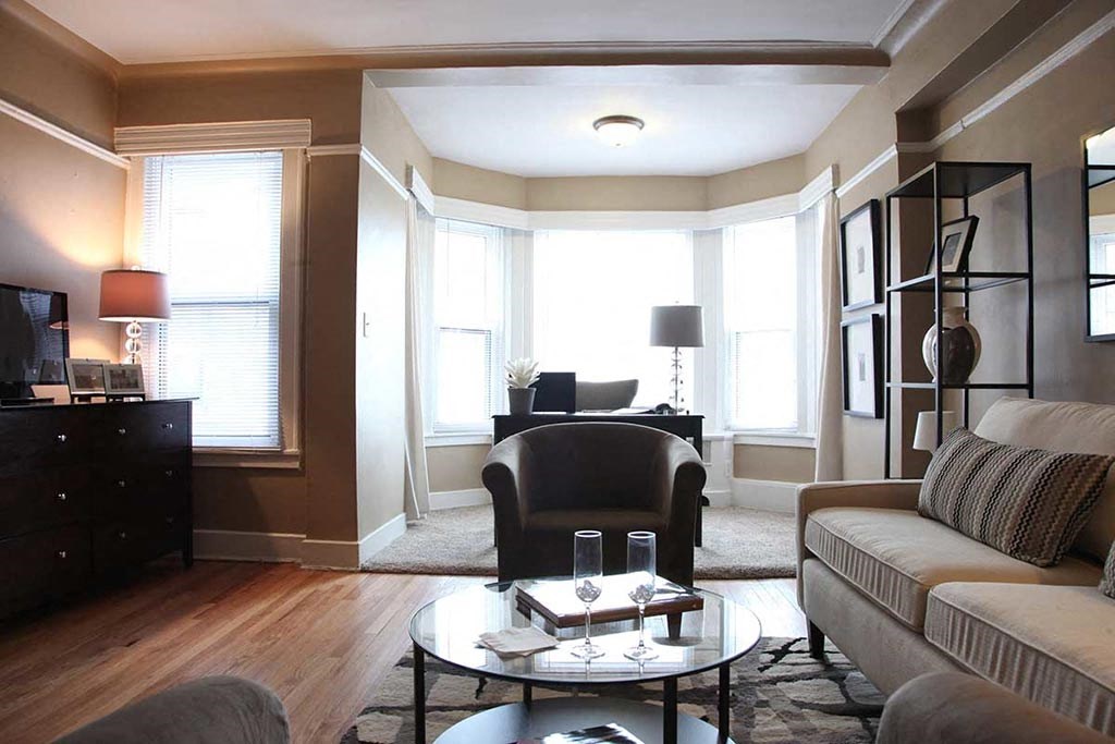 Furnished living room with wood floors and reading nook.