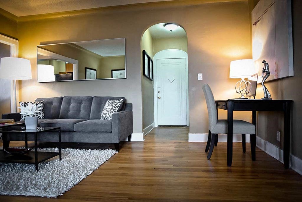 Living room with couch, desk, and arched doorway