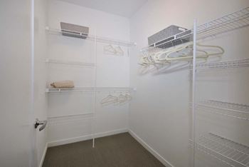 a walk in closet with white walls and shelves