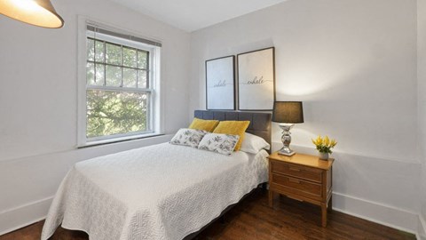 A bedroom with a bed, nightstand, and window.