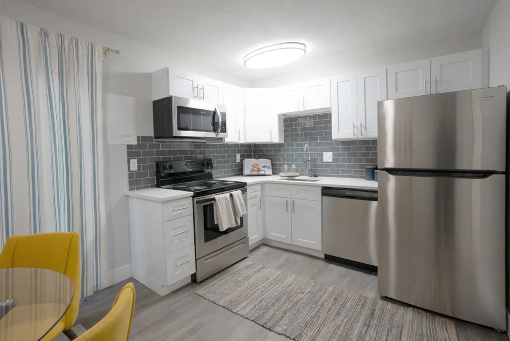 A modern kitchen with a yellow chair and a stainless steel refrigerator.