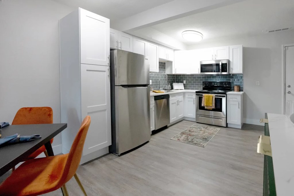 A kitchen with a refrigerator, oven, and sink.