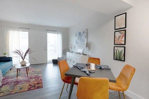 A dining room with a table set for two and a sofa in the background.