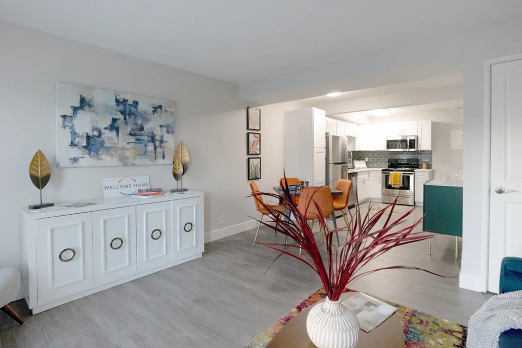 A white cabinet with a sign that says "Welcome" is in a room with a blue and white painting on the wall.