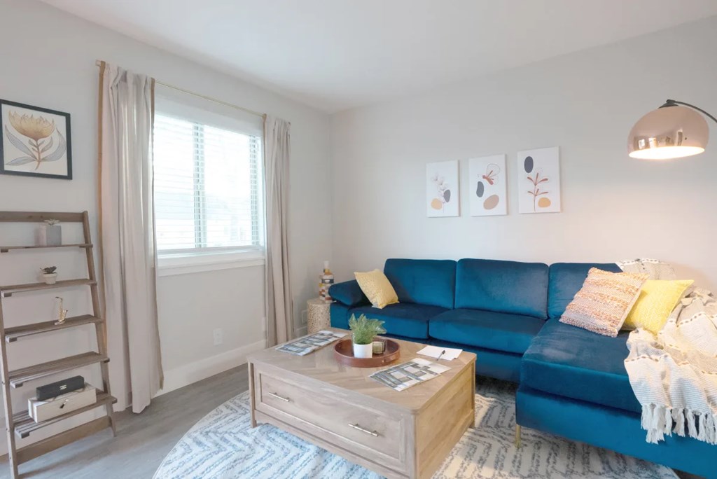 A living room with a blue couch and a wooden coffee table.