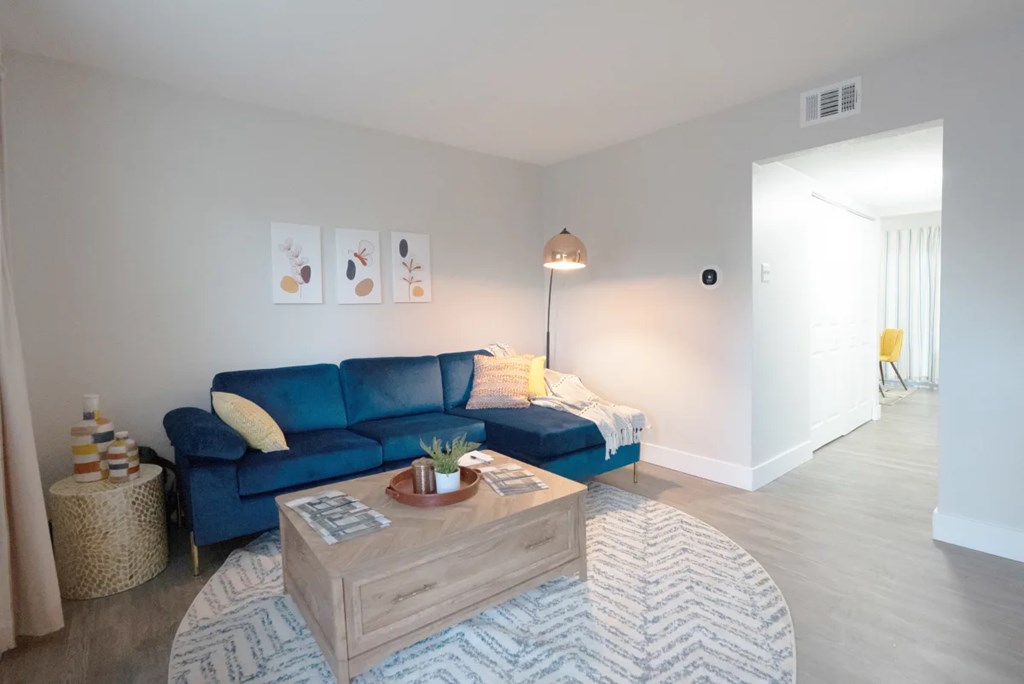 A living room with a blue couch and a wooden coffee table.