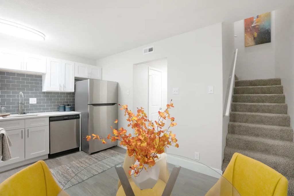A kitchen with a refrigerator, sink, and stove.