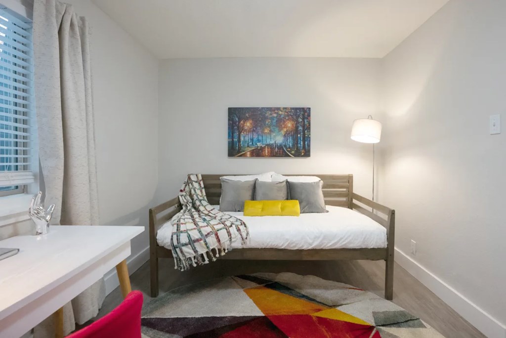 A bedroom with a bed, a desk, and a chair.