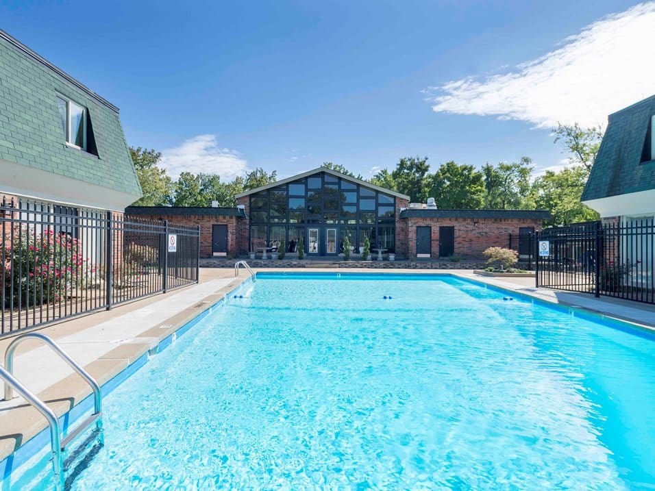 A large outdoor swimming pool surrounded by a black fence.