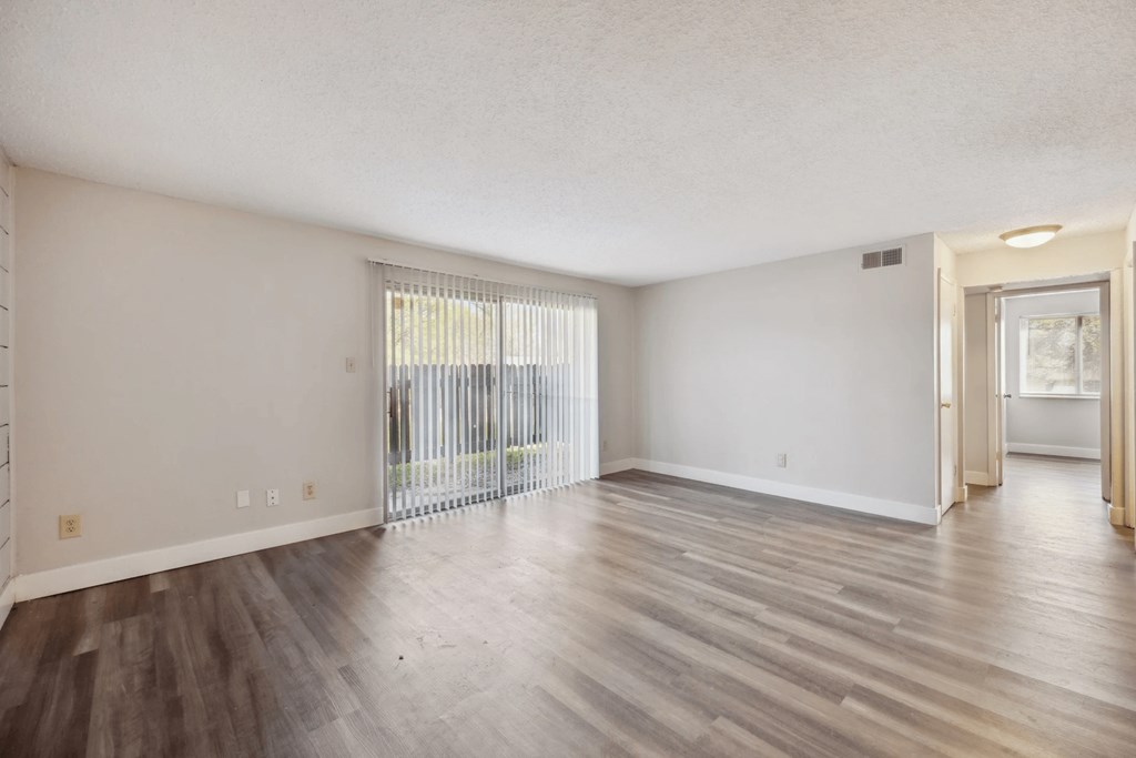 A room with wooden flooring and a sliding glass door.