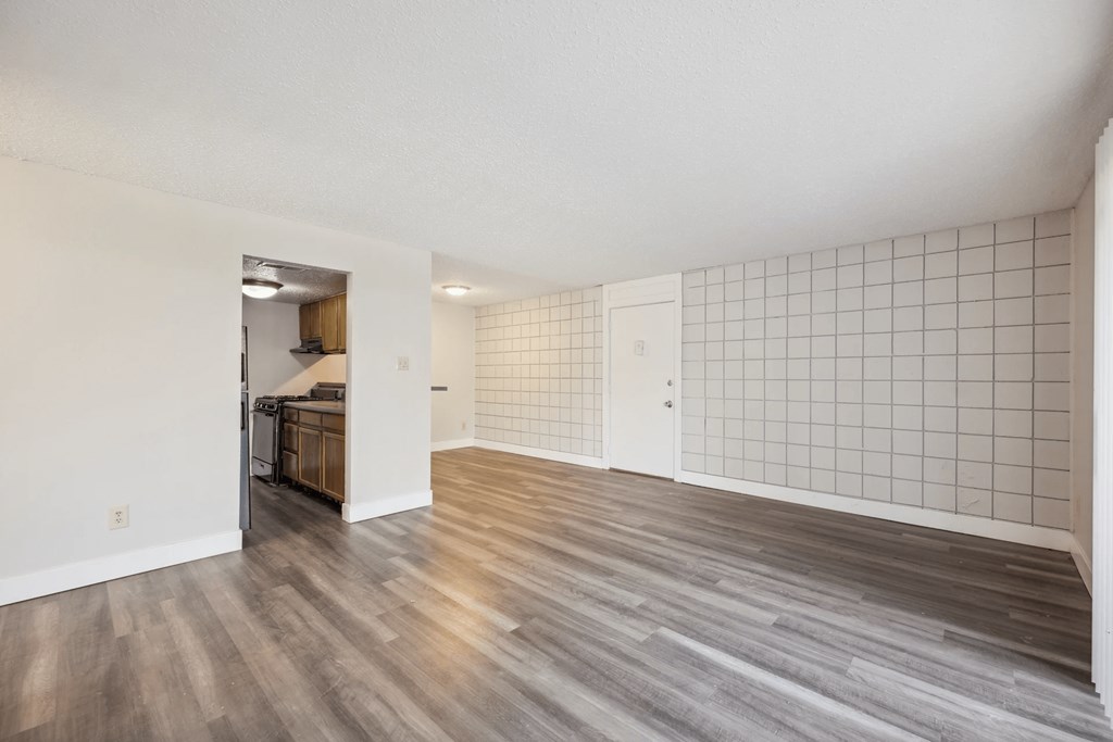 A room with a white tile wall and wood flooring.