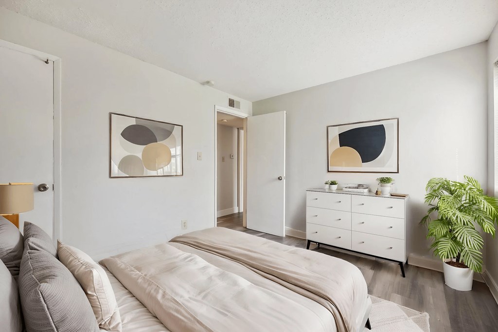 A bedroom with a bed, dresser, and two framed artworks on the wall.