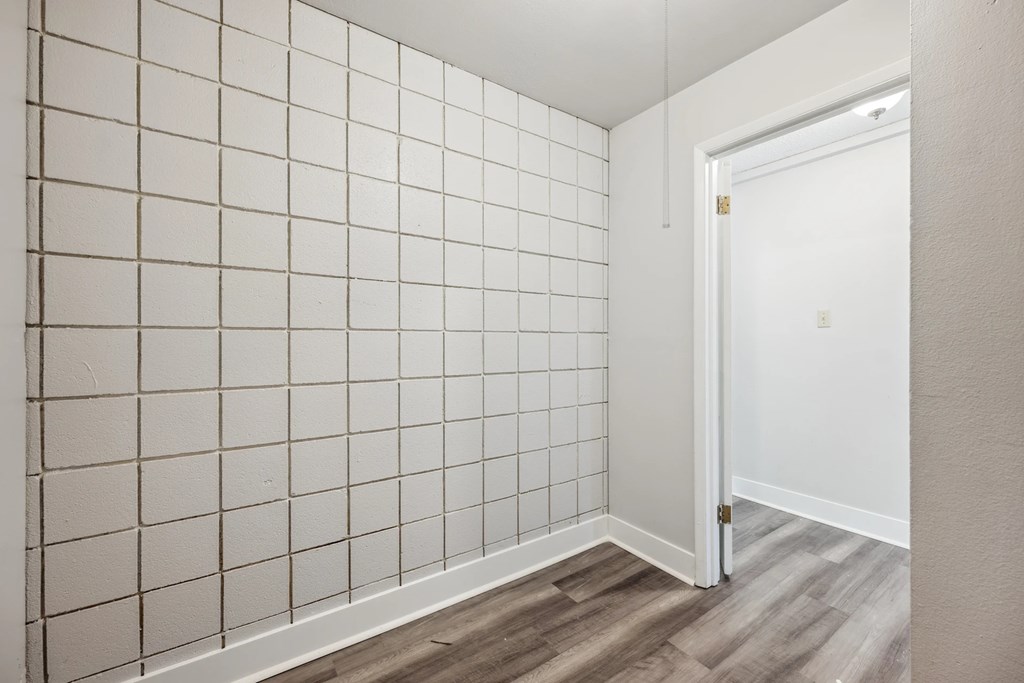 A white tiled wall in a room with a door.