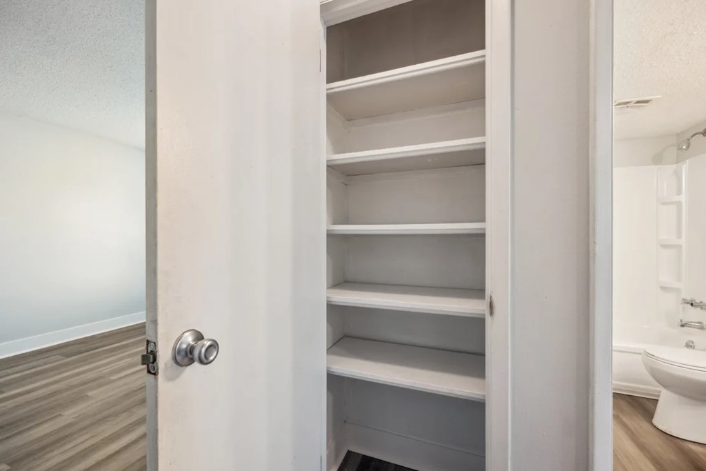 A white door with a silver handle is open to a white bathroom.