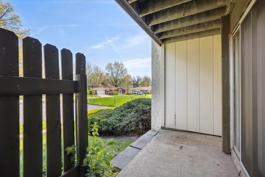 A wooden fence is in the foreground of a bright day.