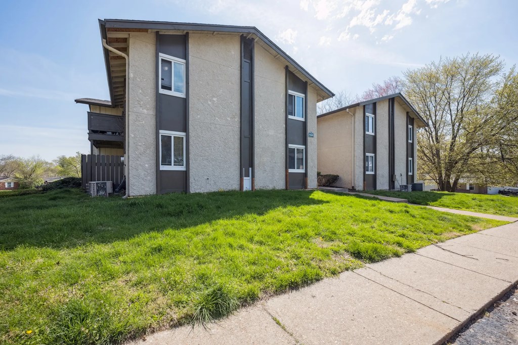 A modern two-story apartment building with a balcony on the second floor.
