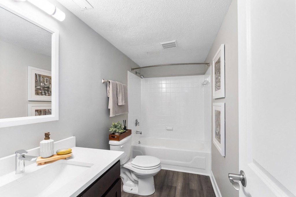 A white bathroom with a toilet, sink, and mirror.