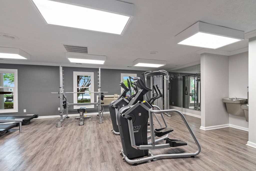A spacious gym with a treadmill, weights, and a bench.