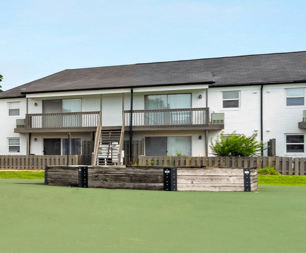 A white building with a balcony and a wooden fence in front.