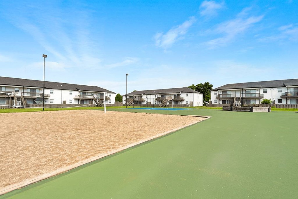 A tennis court is surrounded by apartment buildings.