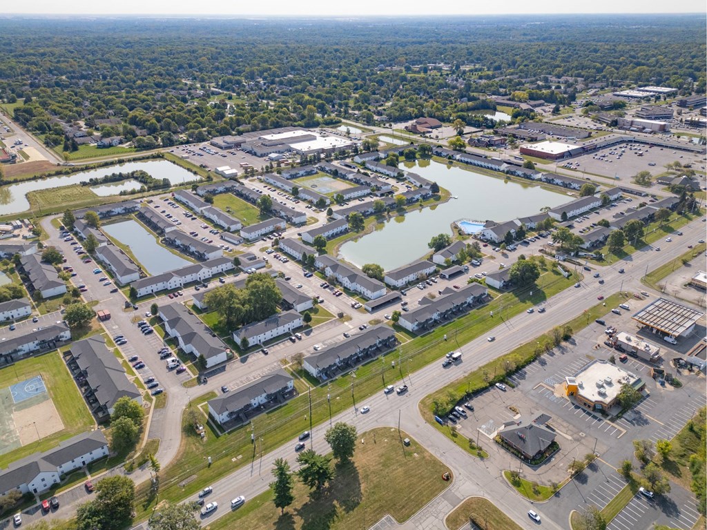 A bird's eye view of a residential area with a lake and apartment buildings.