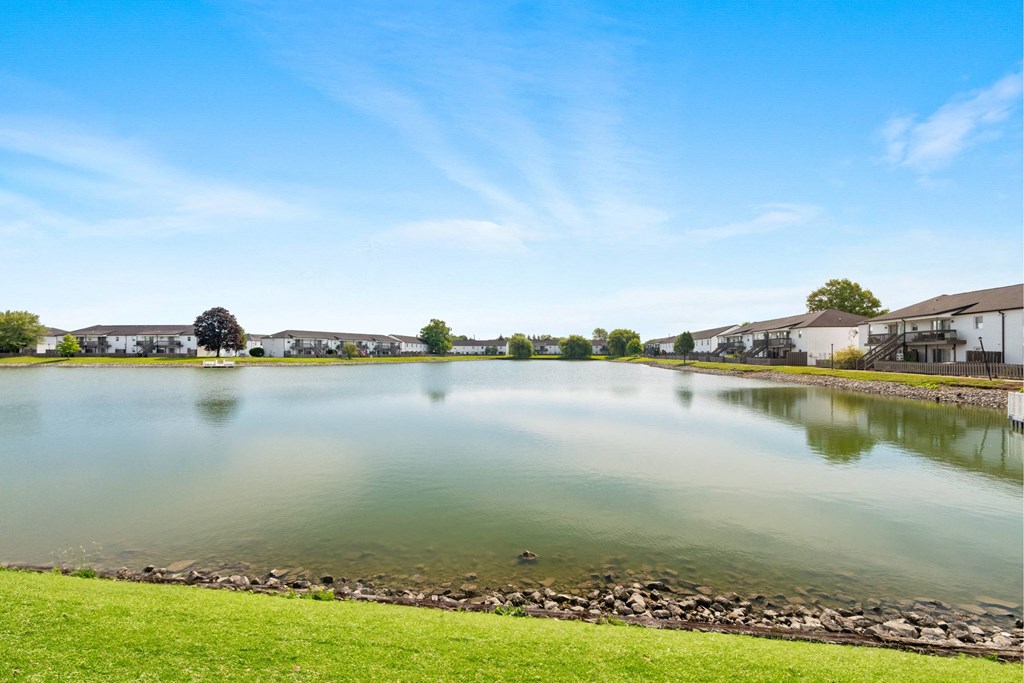 A serene lake surrounded by buildings and a clear blue sky.