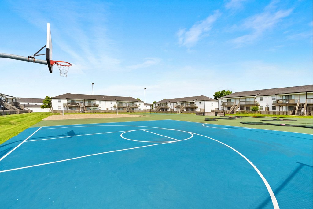 A basketball court with a hoop and a blue surface.