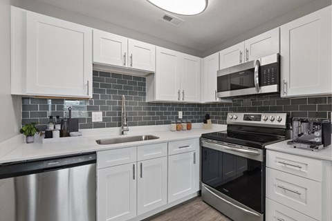 A kitchen with white cabinets and a black stove top oven.