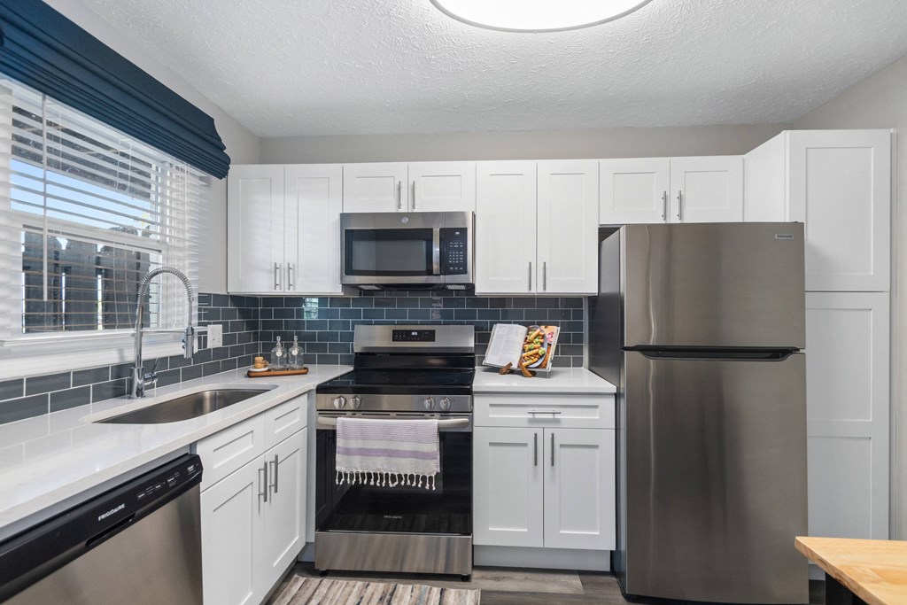 A modern kitchen with a stainless steel refrigerator and white cabinets.