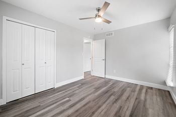 A room with a ceiling fan and wood flooring.