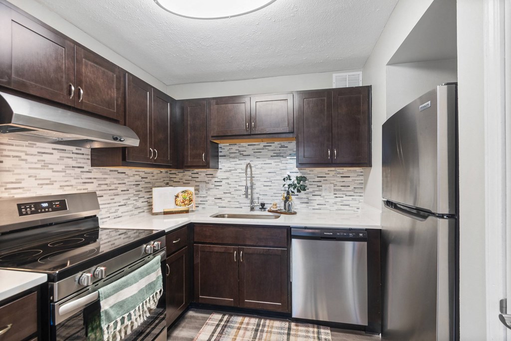 A kitchen with a stove top oven, a refrigerator, and a counter top.