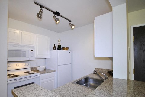 A kitchen with white cabinets and granite countertops.