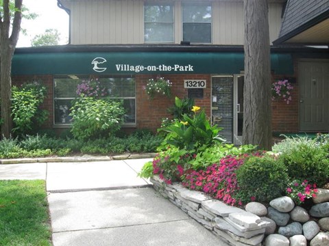 A building with a green awning that says "Village on the Park" and the number 13210.