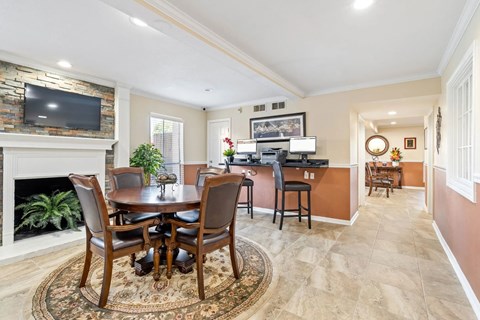 A dining room with a stone fireplace and a television above it.