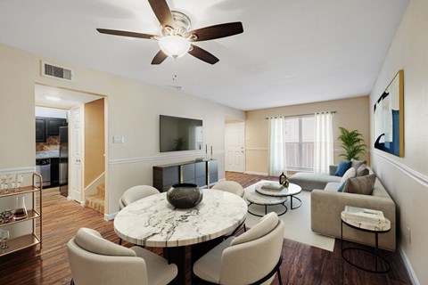 A living room with a white ceiling fan and a round marble table surrounded by chairs.