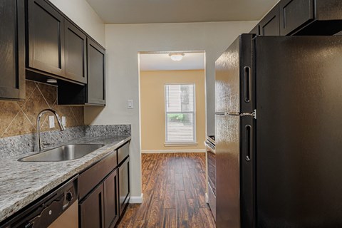 A kitchen with black cabinets and a black refrigerator.