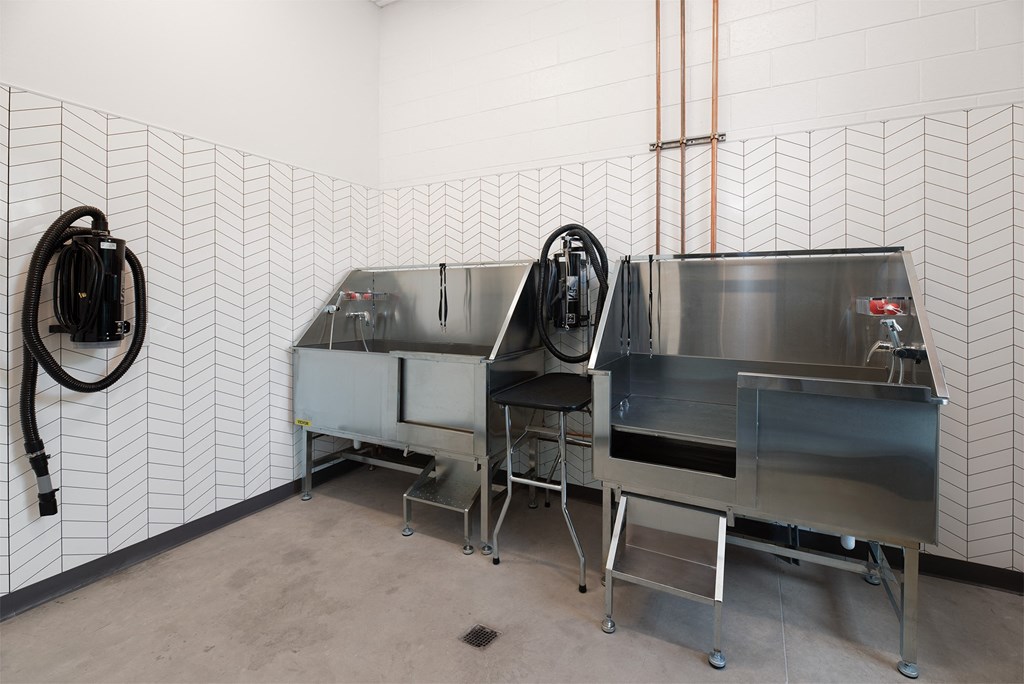 a stainless steel commercial kitchen with two sinks and a hose on the wall