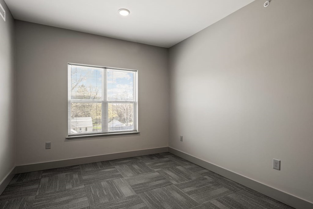 an empty room with a window and wood flooring